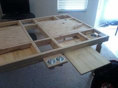 a wooden table with drawers and two bowls on the bottom, in front of a television