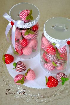 two glass jars filled with strawberries on top of a table