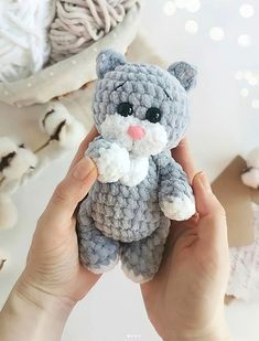 a hand holding a small gray crocheted cat