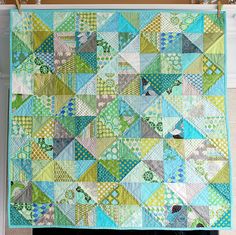 a green and blue quilt hanging on a wall