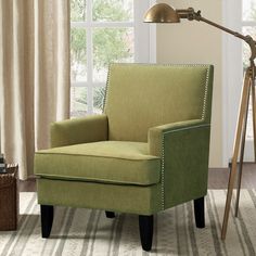 a green chair sitting on top of a rug next to a wooden table and window