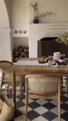 a dining room table and chairs in front of a fireplace with food on the table