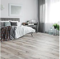 a bedroom with wood flooring and white walls is pictured in this image, there are plants on the side of the bed