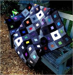 a patchwork quilt sitting on top of a wooden bench next to a pile of hay