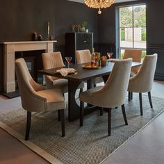 a dining room table with beige chairs and a chandelier hanging from the ceiling