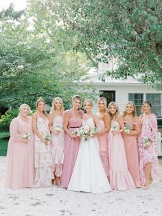 a group of women standing next to each other in front of a white house and trees