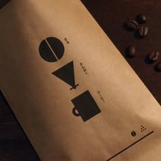 a brown paper bag sitting on top of a wooden table next to some coffee beans