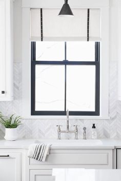 a kitchen with white cabinets, black and white accessories and a large window over the sink