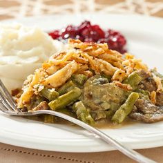 a white plate topped with mashed potatoes and green beans covered in gravy