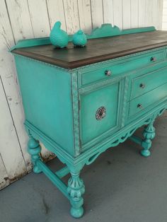 an old dresser with two birds on top