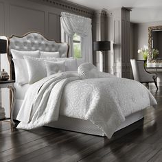 a bed with white comforter and pillows in a room