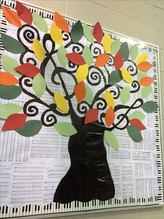 an art project made out of paper and colored leaves on a sheet of music sheets