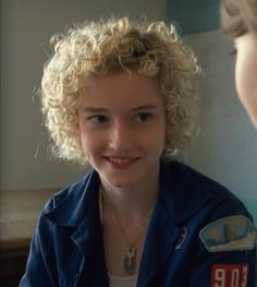 a woman with blonde hair is talking to another woman in a blue shirt and white t - shirt