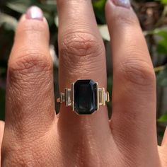 a woman's hand with a ring on it that has an emerald stone in the middle