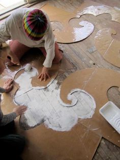 two women are making decorative paper on the floor