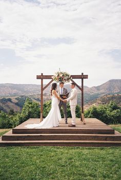 a bride and groom standing at the end of their wedding ceremony on top of a wooden platform