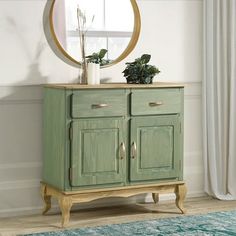 a green cabinet sitting in front of a window with a round mirror on top of it