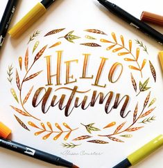 the words hello autumn written in gold foil surrounded by markers and crayon pens