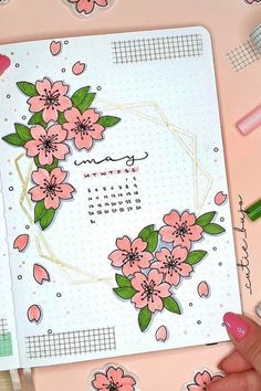 a hand holding a notebook with pink flowers on it