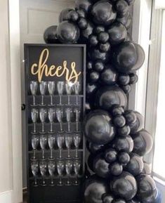 black and white balloons with cheers written on the wall next to a wine glass display