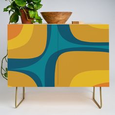 a potted plant sitting on top of a cabinet next to a wooden bowl holder