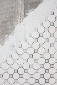 a white and gray tiled wall with grungy paint