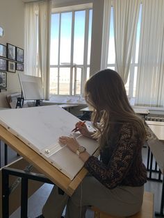 a woman is sitting at a table drawing