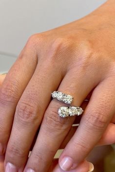 a woman's hand with two wedding rings on her left and the other hand holding an engagement ring