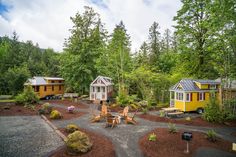 two tiny houses in the middle of a forest with picnic tables and chairs around them