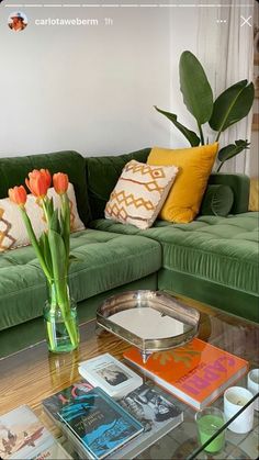 a living room with green couches and flowers in a vase on the coffee table