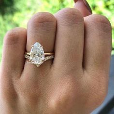 a woman's hand with a ring on it and a pear shaped diamond in the middle