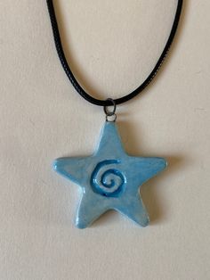 a blue ceramic star with a spiral in the center on a black cord necklace hanging from a leather cord