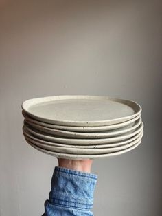 a stack of white plates sitting on top of each other in front of a gray wall