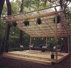 a covered patio with potted plants and lights on the roof is surrounded by trees