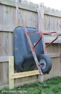 an old suitcase is attached to the back of a cart in a fenced backyard