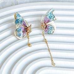 Handmade Blue Purple Butterflies with Drops Earrings These unique handmade earrings feature a beautiful butterfly wing design with purple and blue colors. The drop design adds elegance and style, making these earrings a perfect accessory for any occasion. Great for gifting, these earrings will be sure to wow. As a gift shop, we offer a complimentary gift box for every order. Some details - Size of earring: around 20mm*30mm Materials: Ear stud: gold-plated sterling silver The base of earring: resin The Handmade Blue Purple Butterflies with Drops Earrings are sold on pair of two earrings. About postage: Standard postage When choosing standard postage, we assume this order is for yourself, or you will wrap the item yourself before giving it out as a gift (the complimentary gift box would be p Pink And Blue Butterfly, Butterfly Wing Design, Blue Butterfly Earrings, Blue Butterfly Wings, Unique Handmade Earrings, Wing Design, Butterfly Wing Earrings, Two Earrings, Headpiece Jewelry