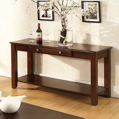 a wooden table with two vases on top of it next to a white wall