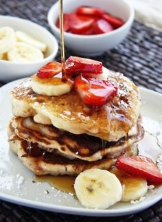 a stack of pancakes topped with bananas and strawberries