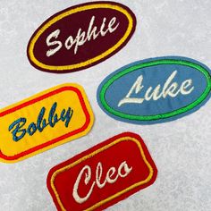 three embroidered patches with names on them sitting on a white tablecloth, one has the word sulphie and the other says luke