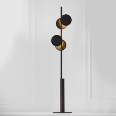 three black and gold lights on a tall pole in front of a white wall or floor