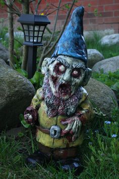 a statue of a zombie in the grass next to a lamp post and some rocks