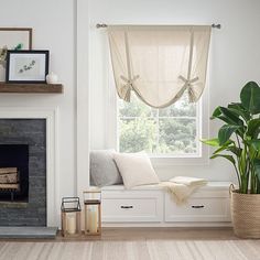 a living room filled with furniture and a fire place next to a window covered in sheer curtains