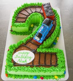 a birthday cake with a train on the top and green grass in the shape of a number