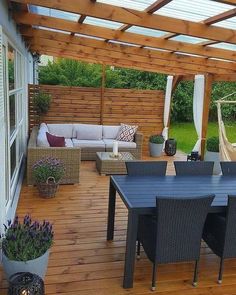 a wooden deck with chairs, table and hammock in the back yard area