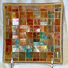 a glass tile wall hanging on the side of a white wall with two metal hooks