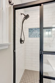 Master bathroom remodel includes glass shower doors with matte-black grids, enclosing an all-tile shower that features a bench seat and Caribbean-blue tiled niche, swarm gray vanity with white marble top, distressed vinyl plank floor, and floating live-edge wood shelving