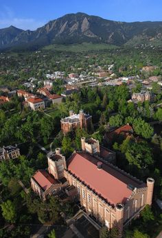 an aerial view of a building surrounded by trees and mountains in the distance is seen from above