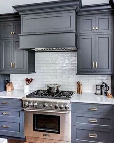 a stove top oven sitting inside of a kitchen next to wooden floors and gray cabinets