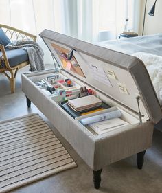 an open suitcase sitting on top of a bed next to a table with books and pens