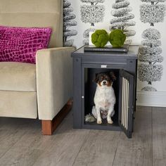 a dog sitting in its kennel next to a chair and wallpaper with trees on it